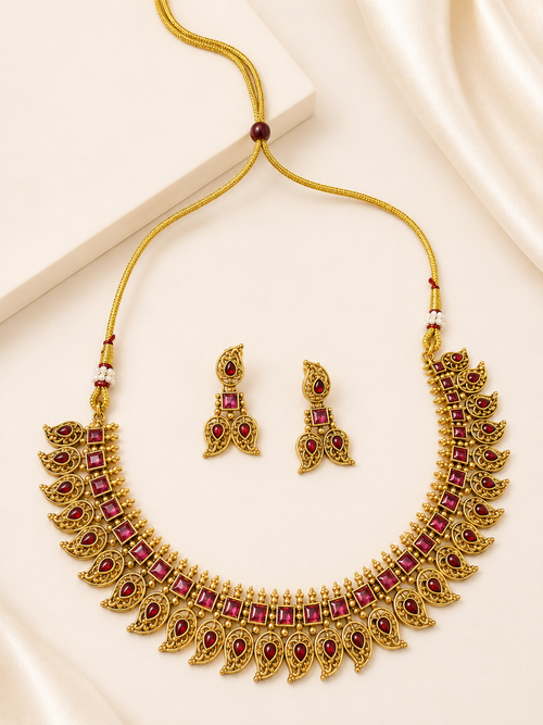 Antique gold-tone imitation temple necklace set with ruby-red acrylic stone inlays, leaf and paisley motifs, and matching drop earrings