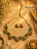 Lakshmi Temple Jewellery Necklace with emerald green stones and matching earrings on golden silk fabric
