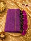 Royal purple mul cotton saree folded showing gold zari stripes and bold magenta tassel pallu fringe on dark net base