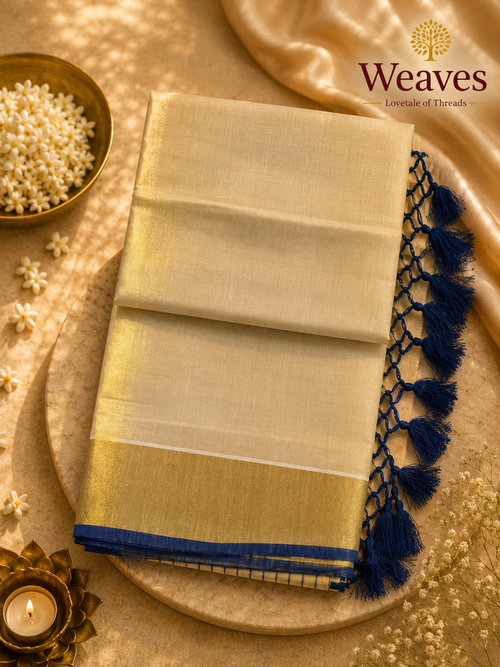 Cream mul cotton kasavu saree showing reverse side with broad gold kasavu border and royal blue tassel pallu fringe