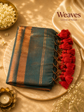 Deep teal mul cotton saree folded showing broad copper zari border stripes and vibrant red tassel pallu fringe