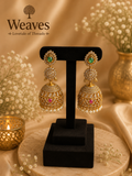 Gold CZ Kundan Jhumka Earrings with emerald green stud top, white CZ dome and pearl drops on black earring stand