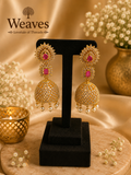 Gold CZ Statement Jhumka Earrings with ruby red stone accents and pearl drops on black earring stand