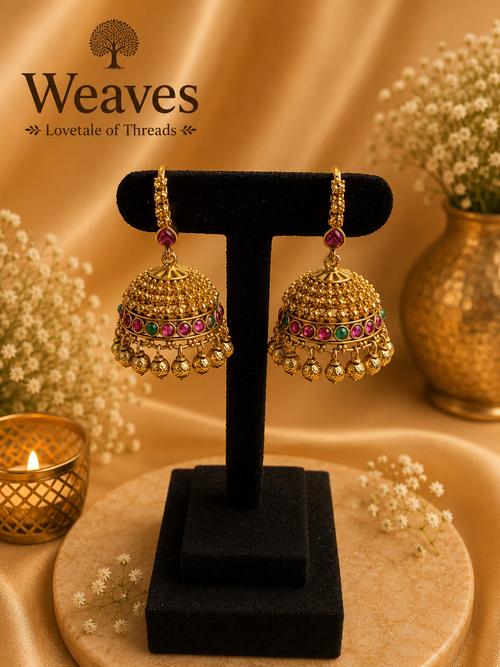 Antique Gold Granule Dome Jhumka Earrings with ruby red and emerald green stone band and gold ball drops on black earring stand