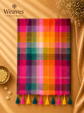 Magenta Madras checks mul cotton saree with colourful tassels displayed on a warm golden backdrop