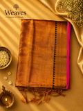 Orange soft tissue saree with a black and golden pallu, pink border, and tassel details
