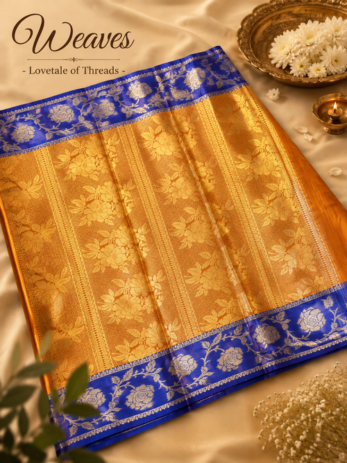 Copper orange soft silk saree with a blue floral pallu and gold-toned detailing