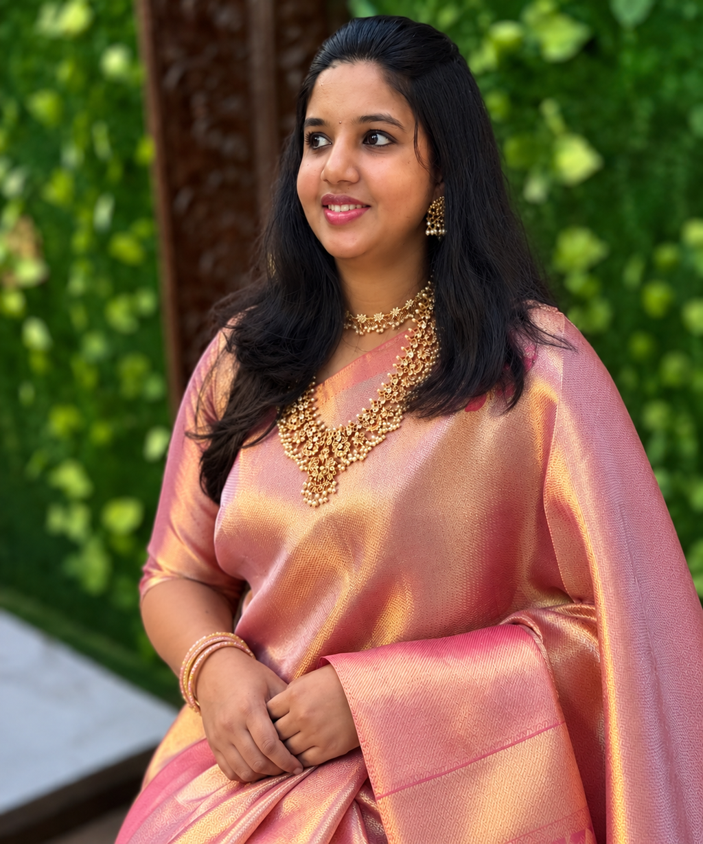 Gold and pastel pink semi tissue silk saree displayed with a graceful drape