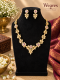 Gold-tone floral necklace and matching earrings with pink stones displayed on a black jewellery bust
