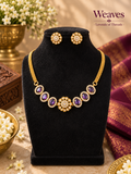 Imitation gold-tone necklace and matching earrings with purple stone-style accents and clear details