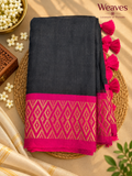 Black mul cotton saree with vivid magenta and gold-toned geometric border and bright magenta tassels